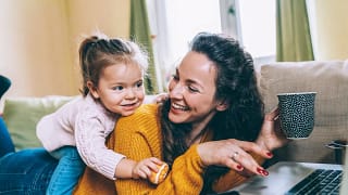 mom on computer with daughter climbing on her.width OikmpJ.jpg