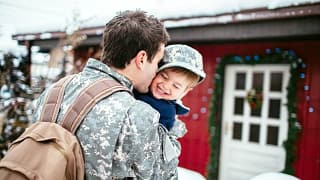 Military father with backpack hugging child o.width CYIFza.jpg
