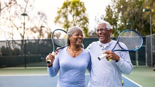 laughing couple holding tennis rackets.jpg