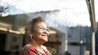 older person looking out a window and smiling.jpg
