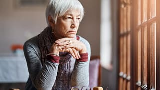 older person sitting at a table looking out a window.jpg