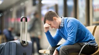 pained young man beside suitcase in airport.width .jpg