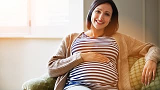 getty pregnant happy smiling on couch.jpg