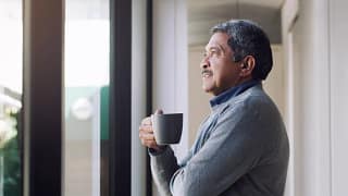older person holding a mug and looking out a window.jpg