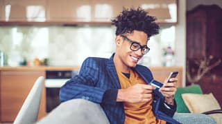 Young man smiles holding credit card XSsJhs.width .jpg