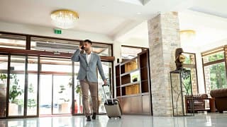 man with suitcase and phone in hotel lobby.width .jpg