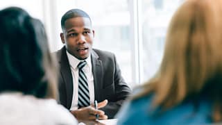 suited businessperson talking to two clients.jpg