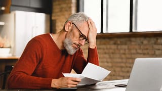older man stressed holding document at laptop gettyimages .jpg