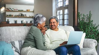 two older people sitting on a couch using a laptop and smiling.jpg
