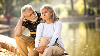 two older people sitting outside looking serious.jpg