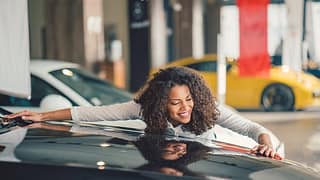Happy person hugging car at a dealer lot. jhm.width .jpg