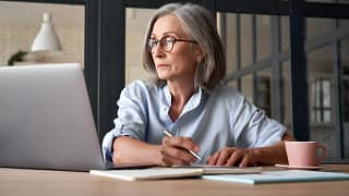 a person at a laptop holding a pen gettyimages .jpg