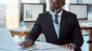getty person in suit at desk laptop thoughtful thinking x cf.jpg