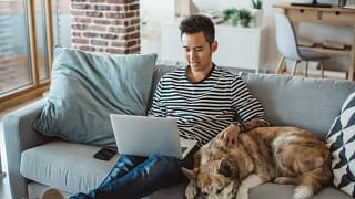young man on laptop on couch with dog Lvpg.width .jpg