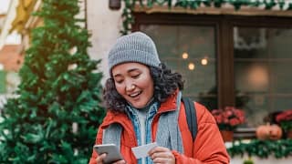 young woman outdoors smiling with phone and c.width zIAeLdf.jpg