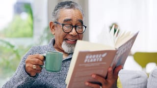 getty smiling happy reading book with mug.jpg