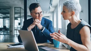 two businesspeople talking in front of a laptop.jpg