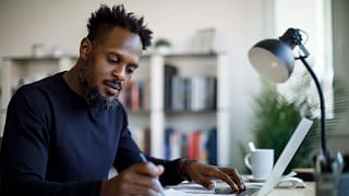 person sitting at a desk looking at a laptop and documents.jpg