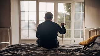 retired man with cane sitting on bed.jpg