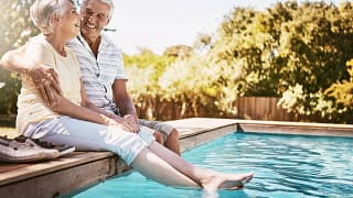 smiling seniors sitting by a pool.jpg