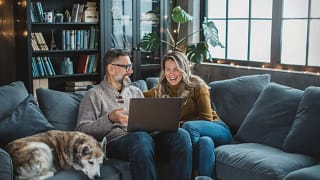 two older people sitting on a couch looking at a laptop.jpg
