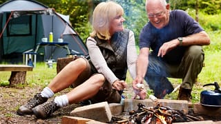 smiling couple roasting marshmallows at campsite.jpg
