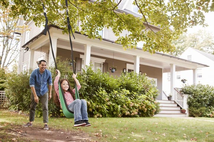 dad pushing daughter in swing in front yard.width .jpg