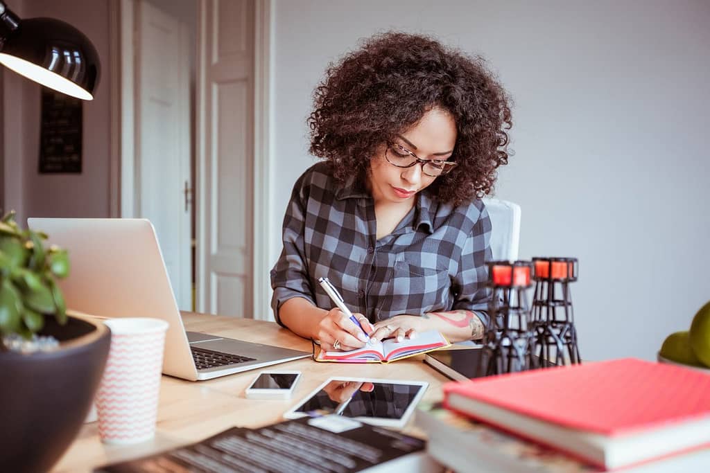 Woman taking notes while using a laptop IpOrU.width .jpg