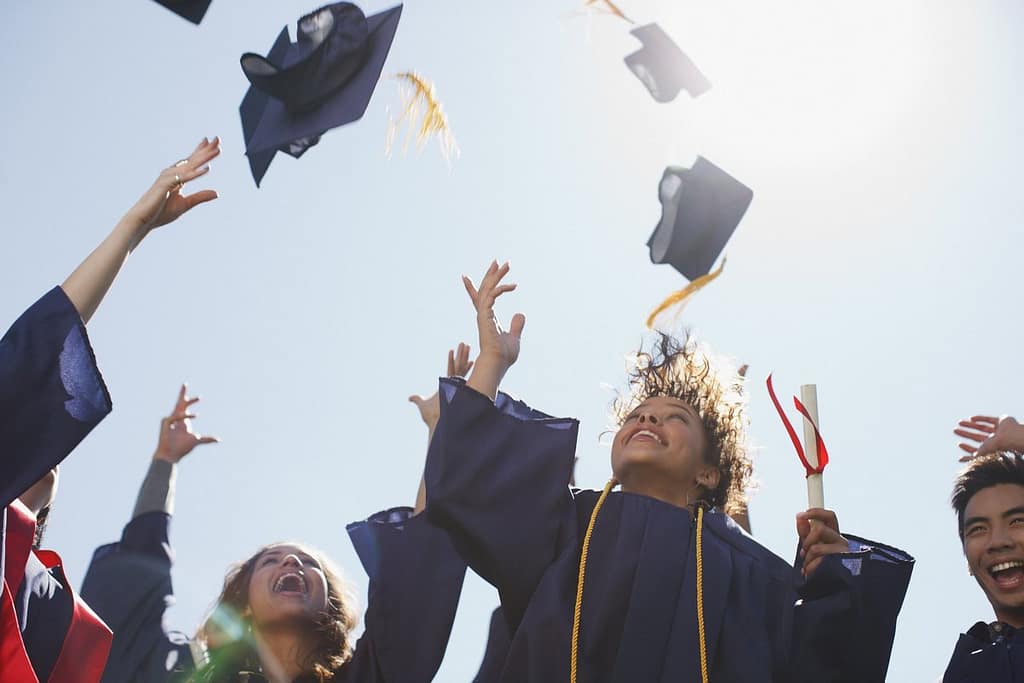 college graduates throwing mortarboards into .width mAUVTM.jpg