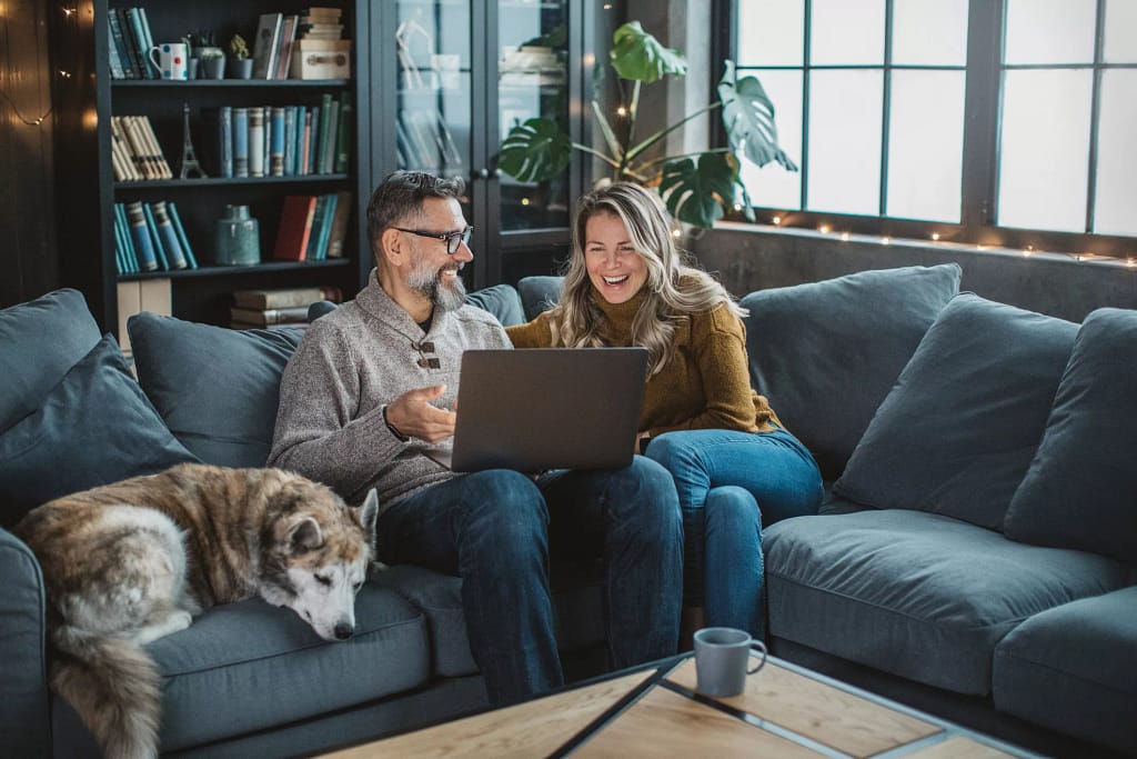 two older people sitting on a couch looking at a laptop.jpg