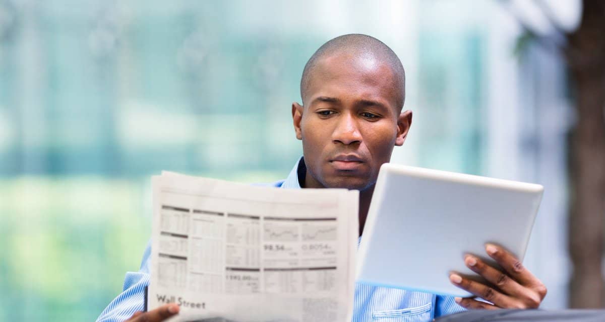 Man reading newspaper and looking at a tablet.width dtWRvy.jpg