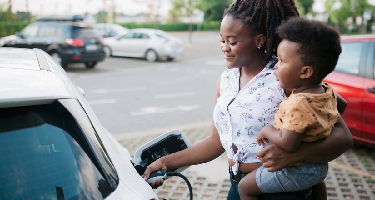 Mother holding her son while charging her ele.width