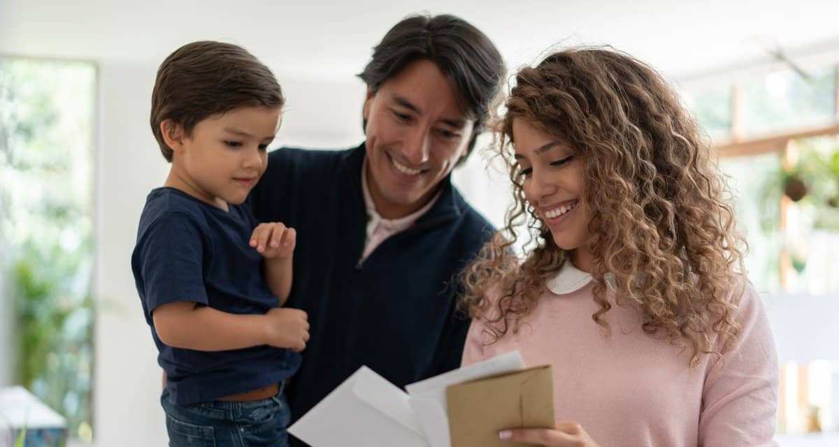 Young family smiles while looking through mai.width YCkchbc