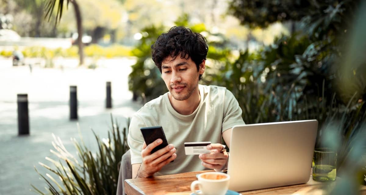 person at outdoor cafe table with laptop phon.width AODczLu.jpg