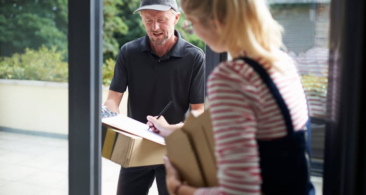 Woman signing for packages with a delivery pe.width VWyGgX.jpg
