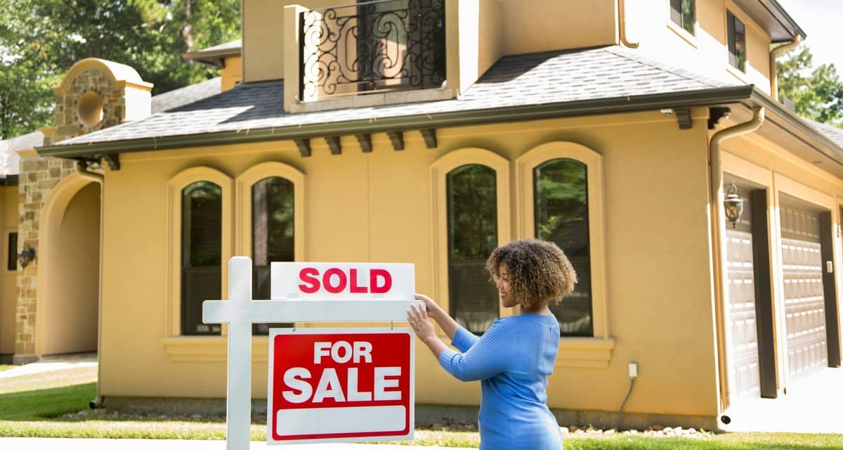 person putting sold sign in front of house T.width .jpg