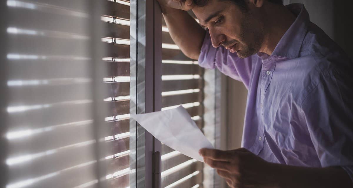 Man looks saddened by paper that hes reading .width .jpg