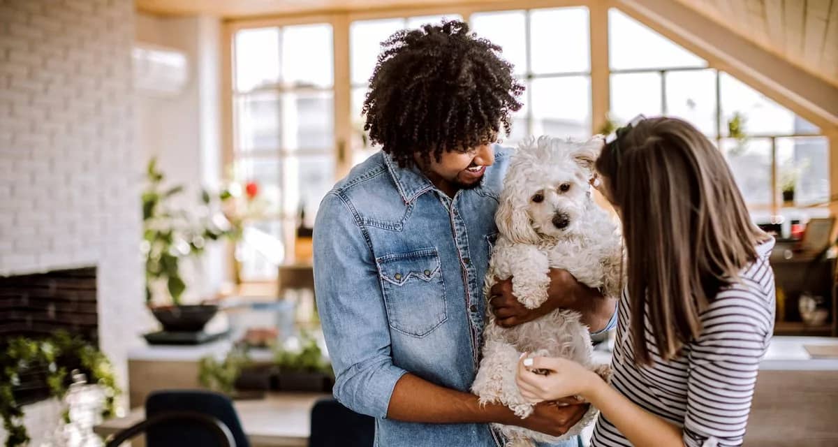 Millennial couple holding dog inside home io.width .jpg