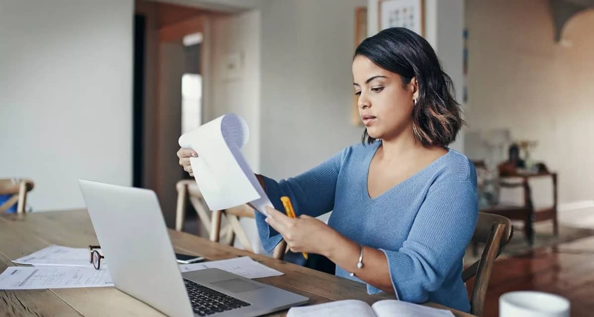 woman with bills and laptop in kitchen EEKd.width .jpg