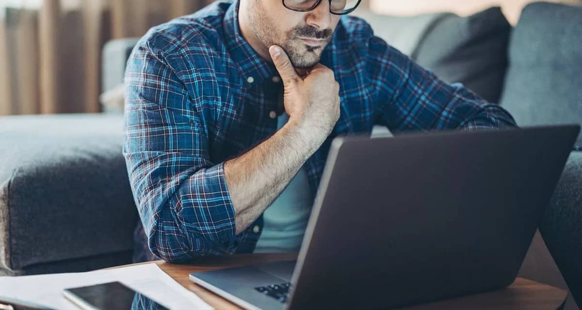 Man with glasses looking at laptop kjgn.width .jpg