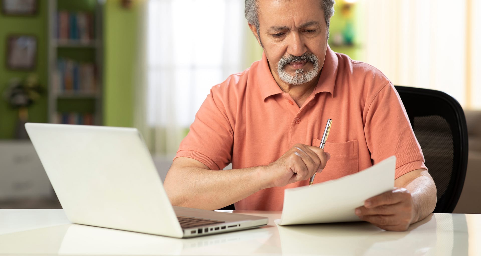 mature person holding pen and looking at document SSdMn