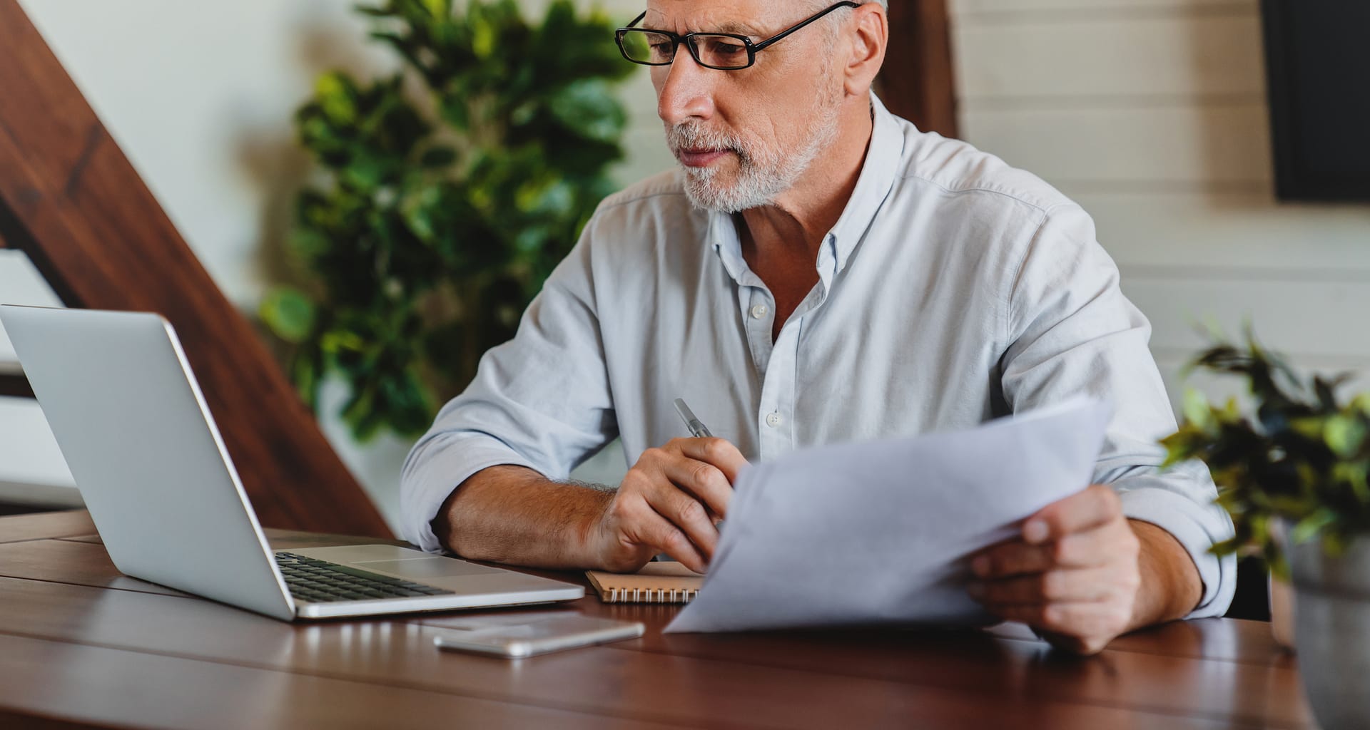 older man laptop holding papers gettyimages