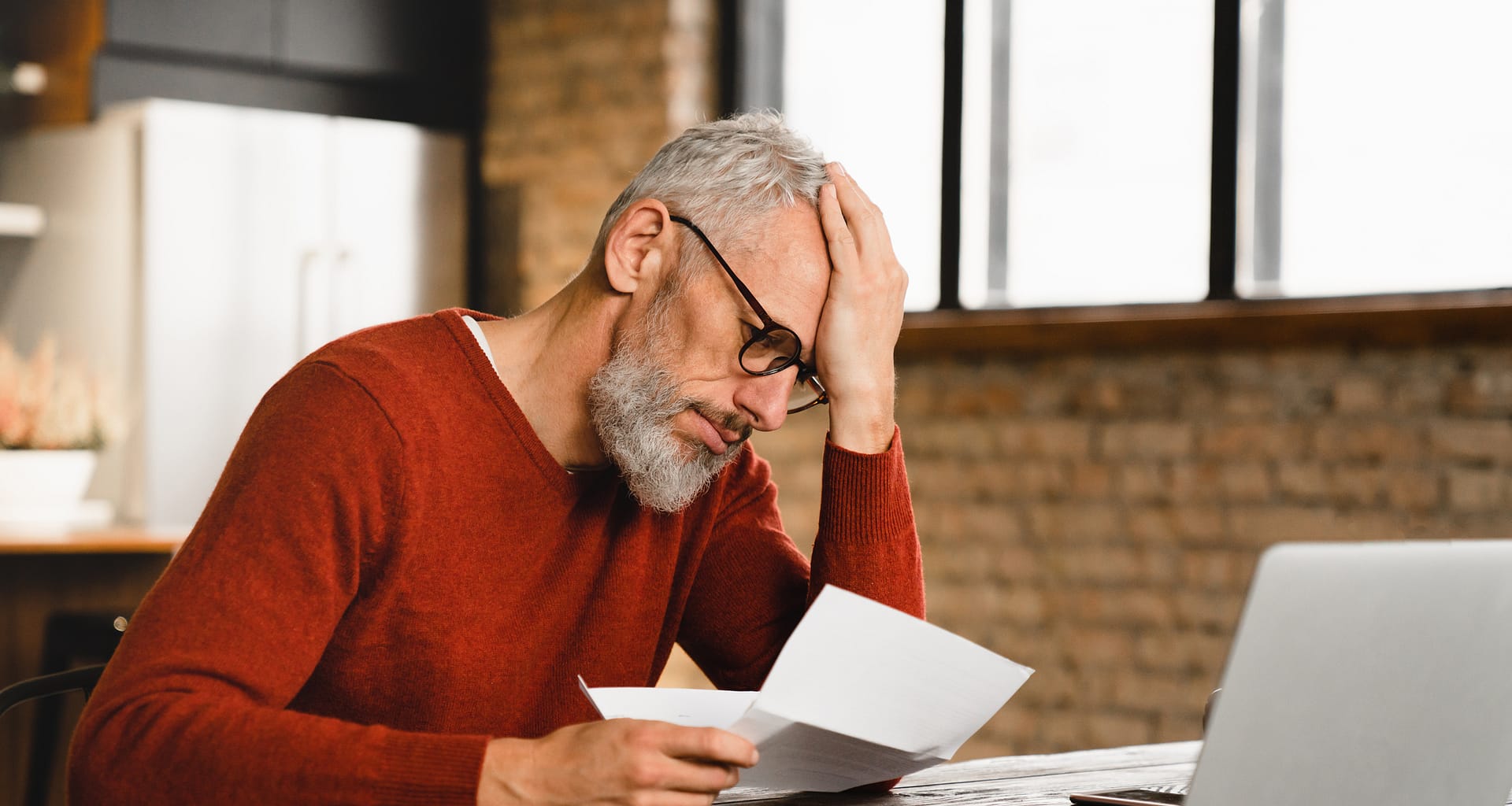 older man stressed holding document at laptop gettyimages