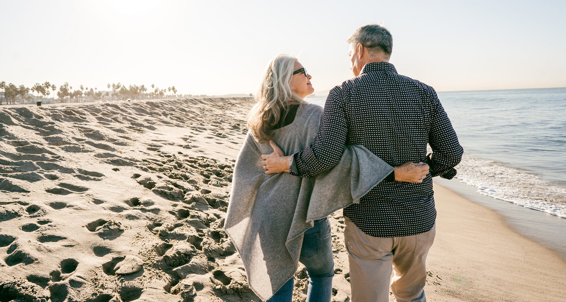 two people walking on the beach hugging