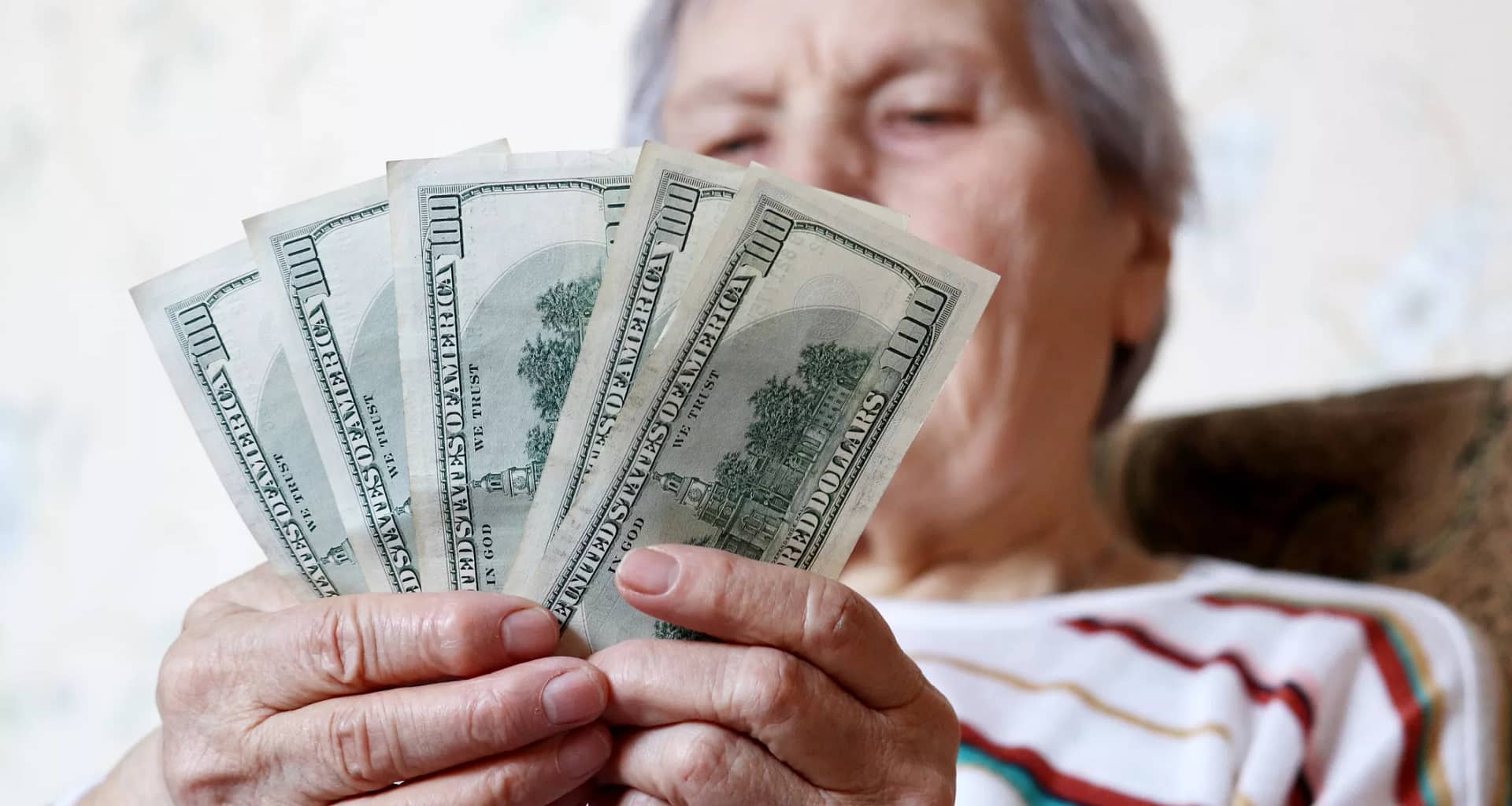 elderly woman retirement social security holding one hundred dollar bills cash getty.jpg