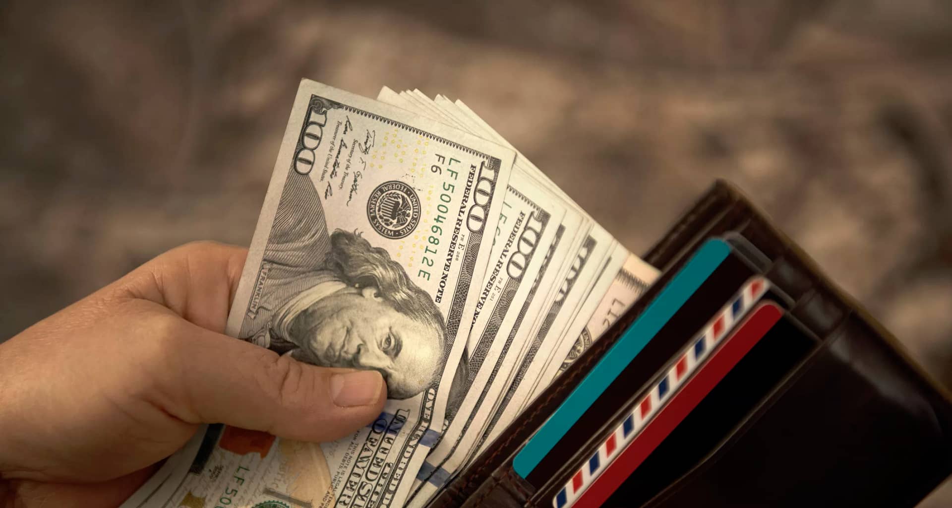 person placing hundred dollar bills into a wallet.jpg