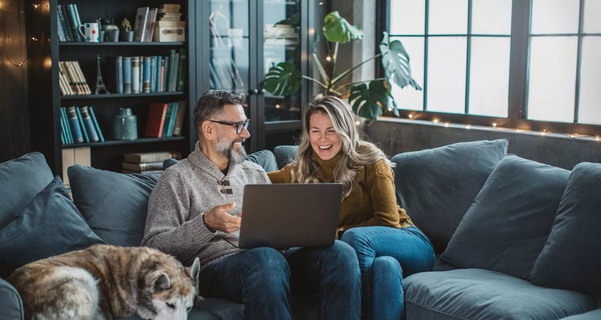 two older people sitting on a couch looking at a laptop.jpg