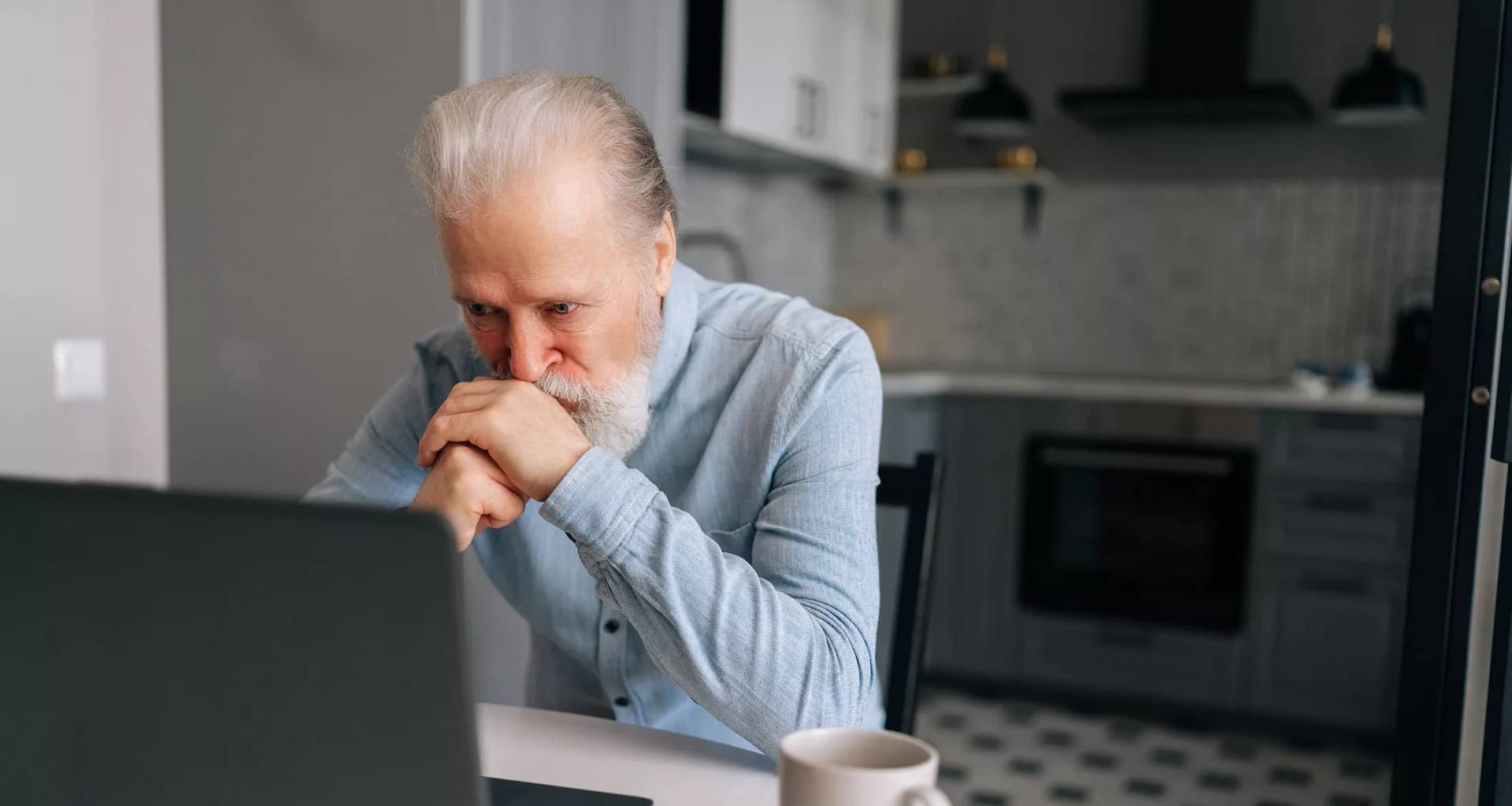 senior man laptop kitchen serious gettyimages .jpg