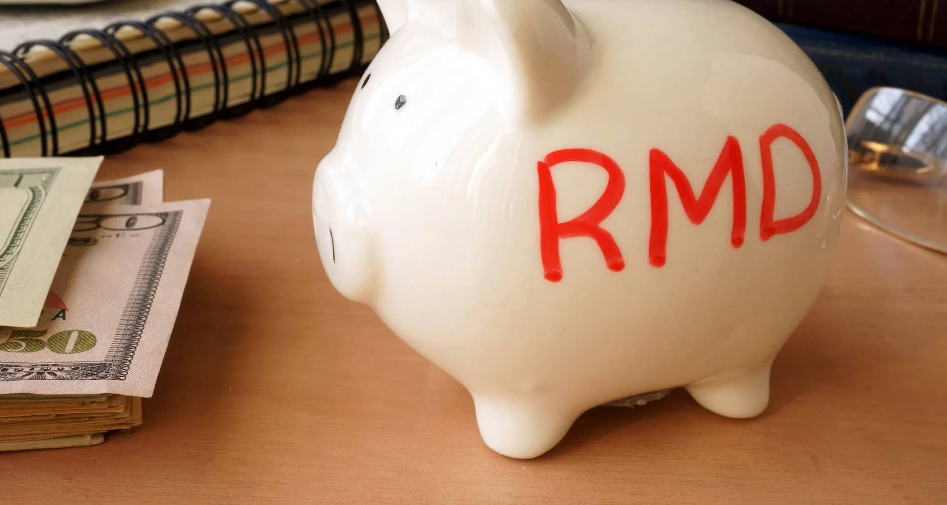 piggy bank with rmd written on its side next to stack of paper money retirement savings k ira cash.jpg