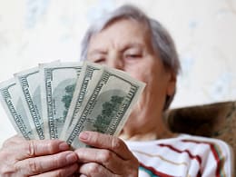 elderly woman retirement social security holding one hundred dollar bills cash getty.jpg